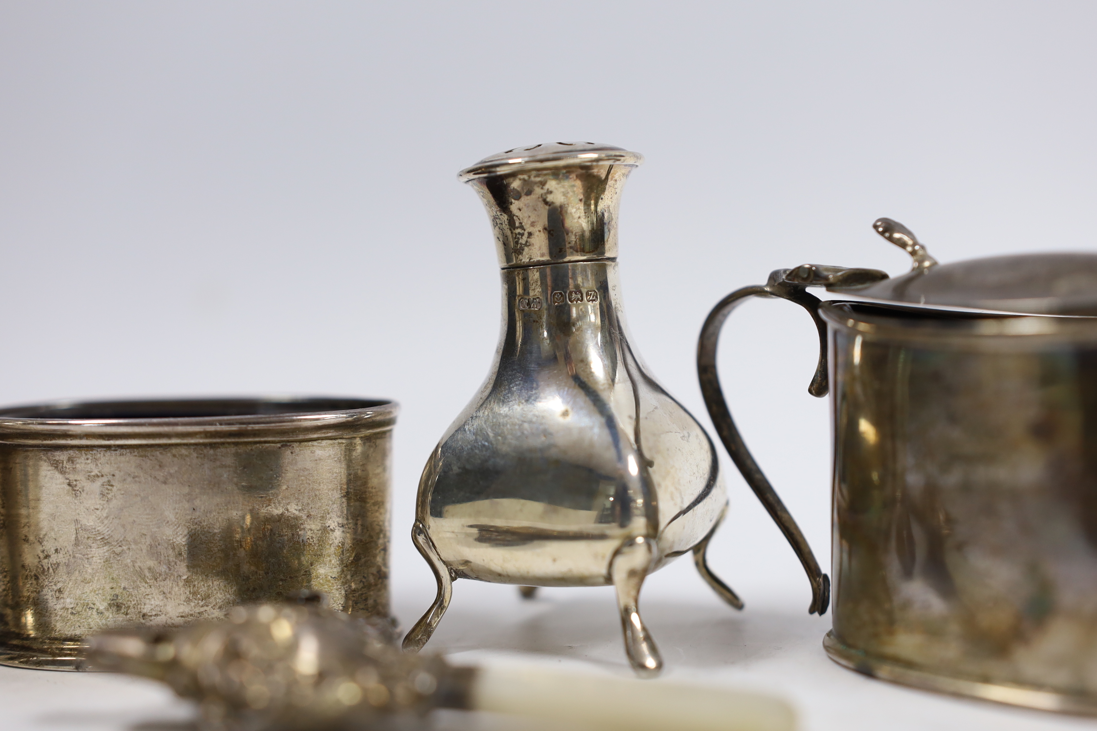 Four assorted silver cruets and a silver child's rattle.